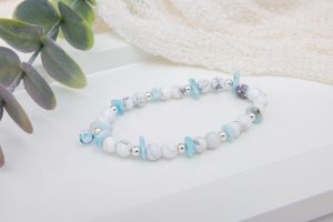 Handmade howlite and larimar chip bracelet with sterling silver beads and an aquamarine birthstone bead centerpiece on a soft, ocean-inspired background.